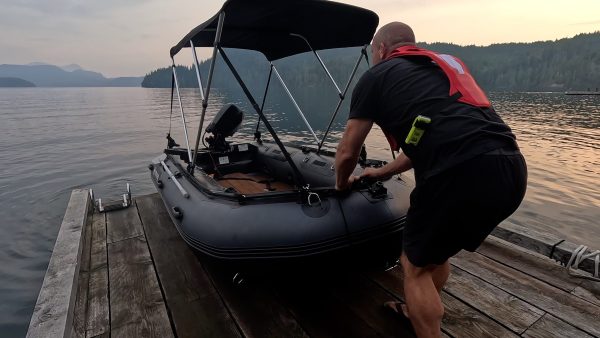 man pulling an inflatable dinghy to shore after a lovely day on the water