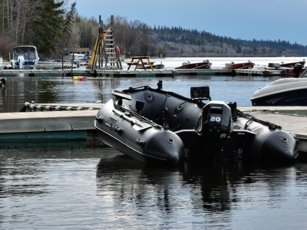 grey inflatable boat docked on a lake