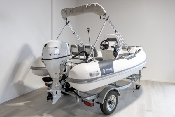 white rigid hull inflatable boat with bimini, integrated console and tohatsu outboard on road runner trailer