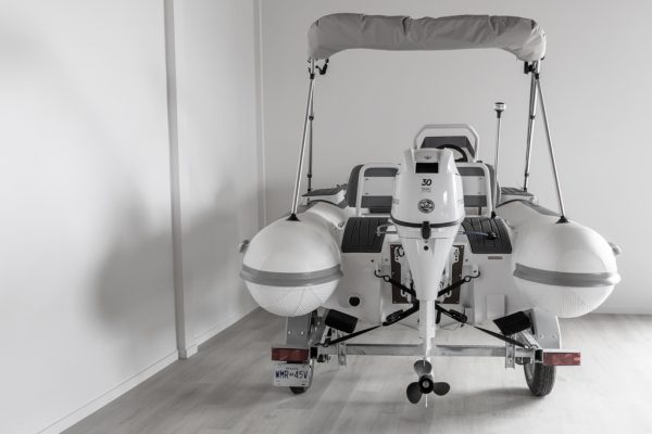 white rigid hull inflatable boat with bimini, integrated console and tohatsu outboard on road runner trailer