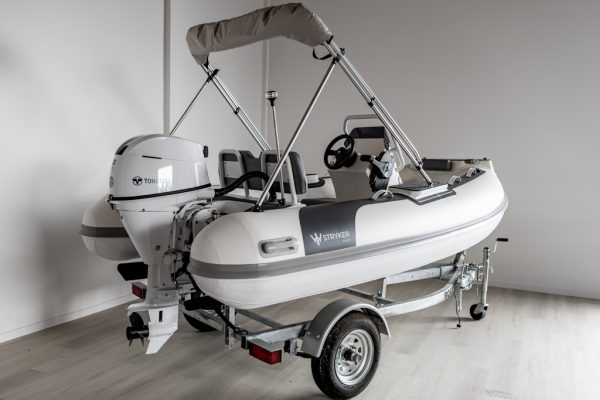 white rigid hull inflatable boat with bimini, integrated console and tohatsu outboard on road runner trailer