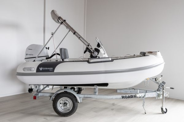 white rigid hull inflatable boat with bimini, integrated console and tohatsu outboard on road runner trailer