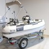 white rigid hull inflatable boat with bimini, integrated console and tohatsu outboard on road runner trailer