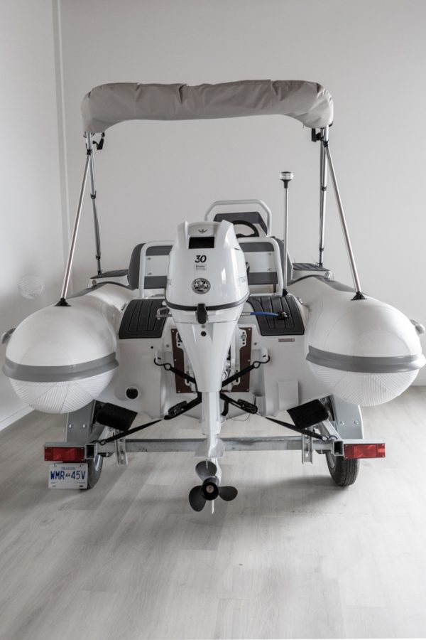 white rigid hull inflatable boat with bimini, integrated console and tohatsu outboard on road runner trailer